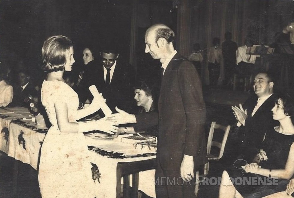 Professor Waldomiro Liessem entrega certificado de conclusão de curso para a sua filha Aurélia, em 1964 . 
À mesa, sentados da esquerda a direita: a senhora Ingrun (nascida Klagges) Seyboth; Dr. Friedrich Rupprecht Seyboth e a professora Seliria Rieger Sphor. 
Imagem: Acervo Heiderose Liessem - FOTO 7 - 
